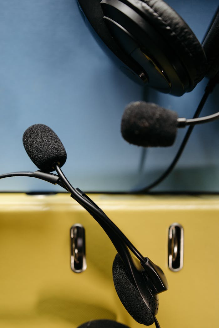 services-01 Close-up of headset microphone and headphones on blue and yellow background.